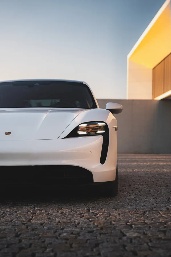 Bílé Porsche u žluté moderní architektury